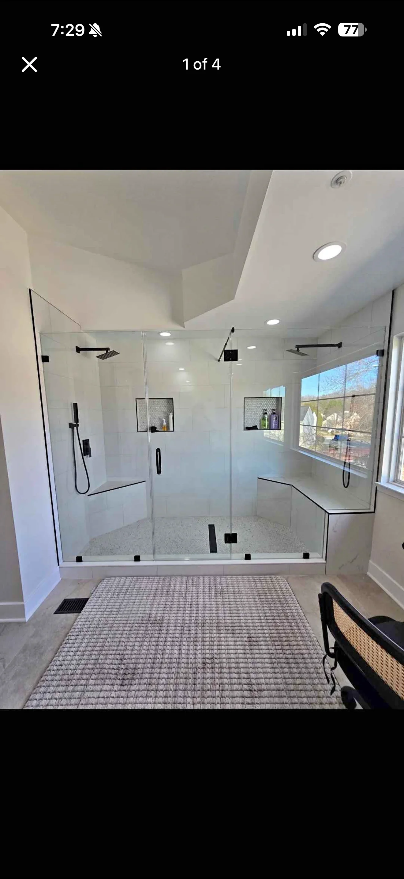 Modern frameless glass shower enclosure with black fixtures and white tile surround