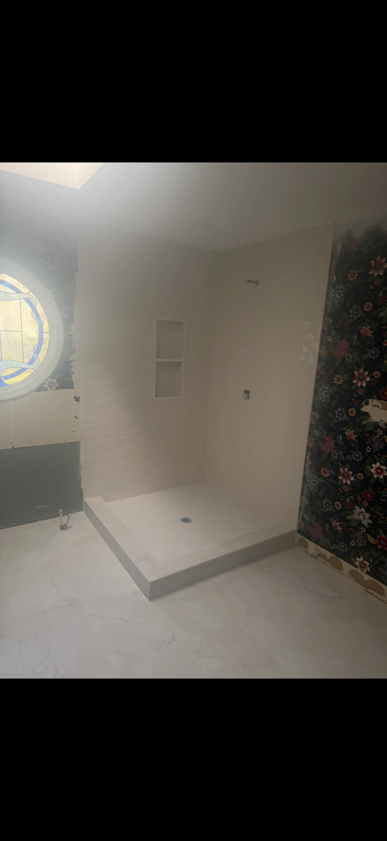 Frameless glass shower enclosure with white base in modern bathroom