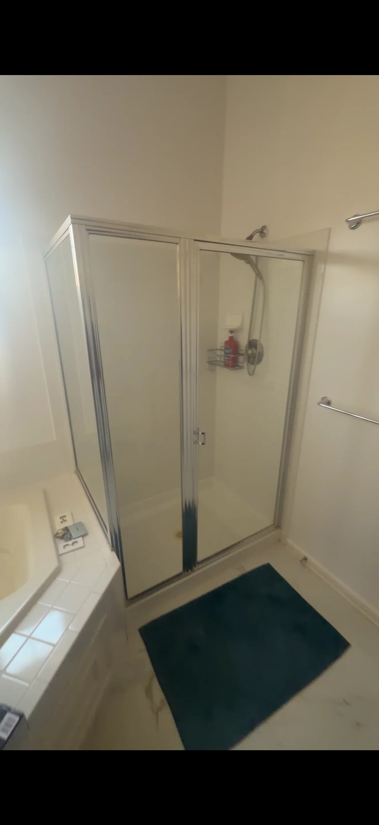 Framed glass shower enclosure with sliding doors and chrome fixtures in bathroom