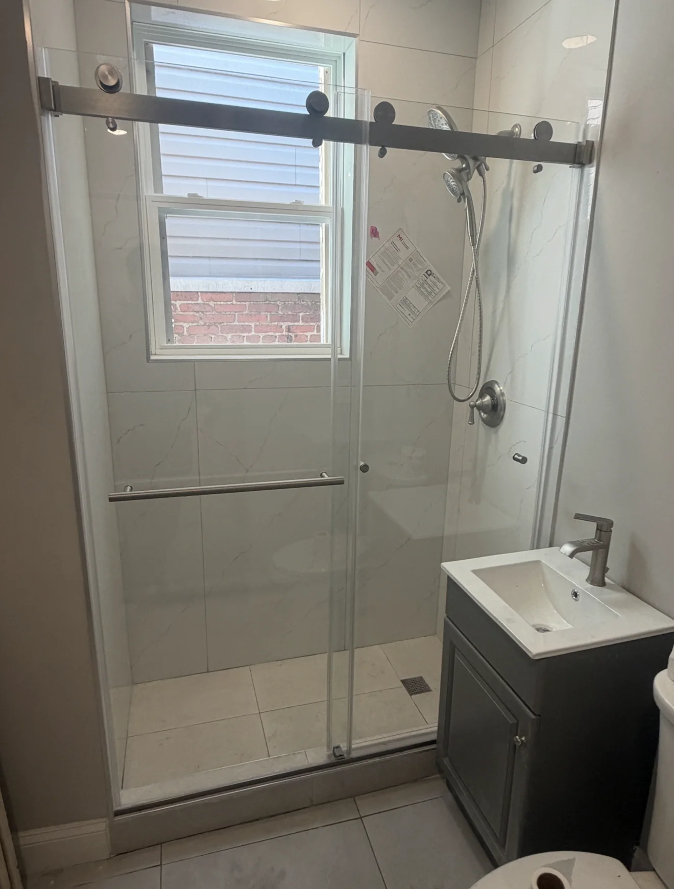 Frameless glass shower enclosure with black sliding track and chrome hardware in modern bathroom