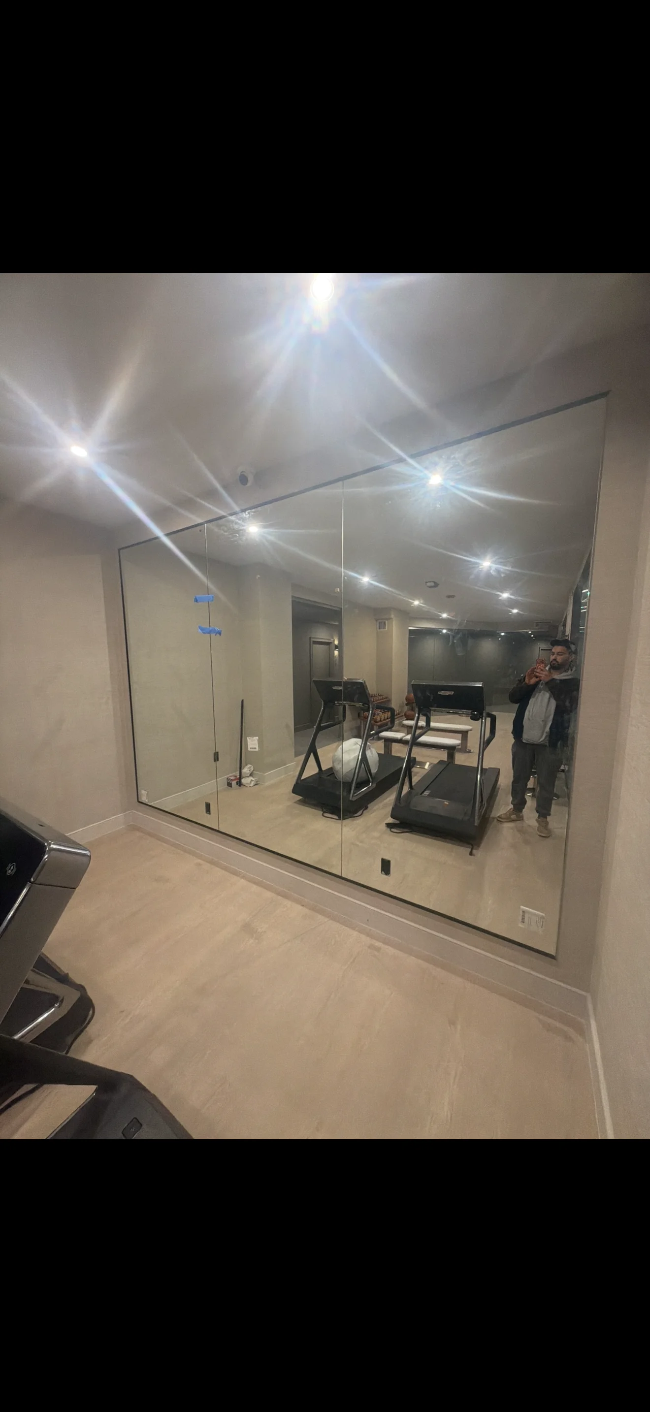 Frameless glass gym enclosure with LED lighting and treadmills visible inside
