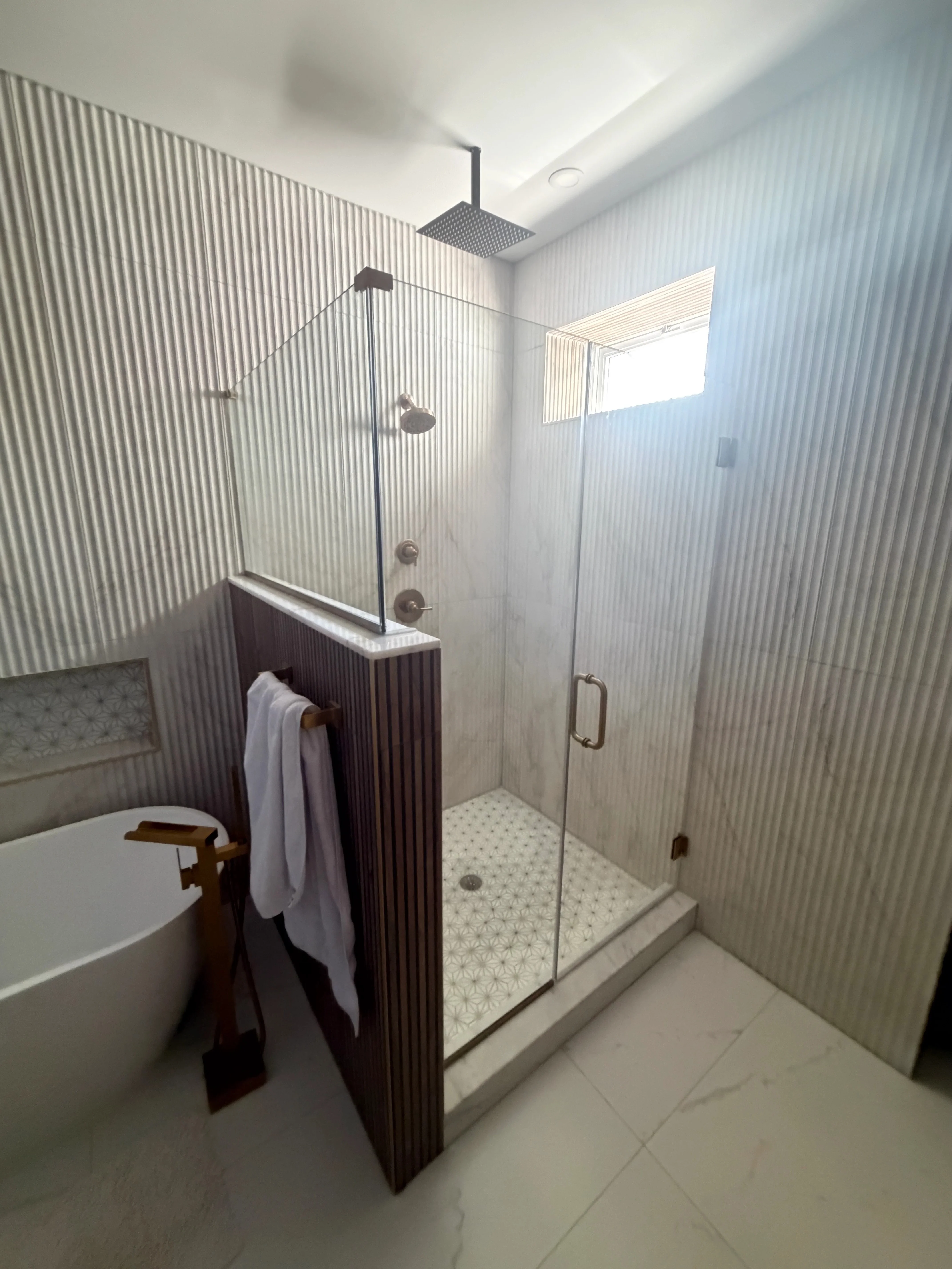 Frameless glass shower enclosure with brushed nickel fixtures in modern bathroom
