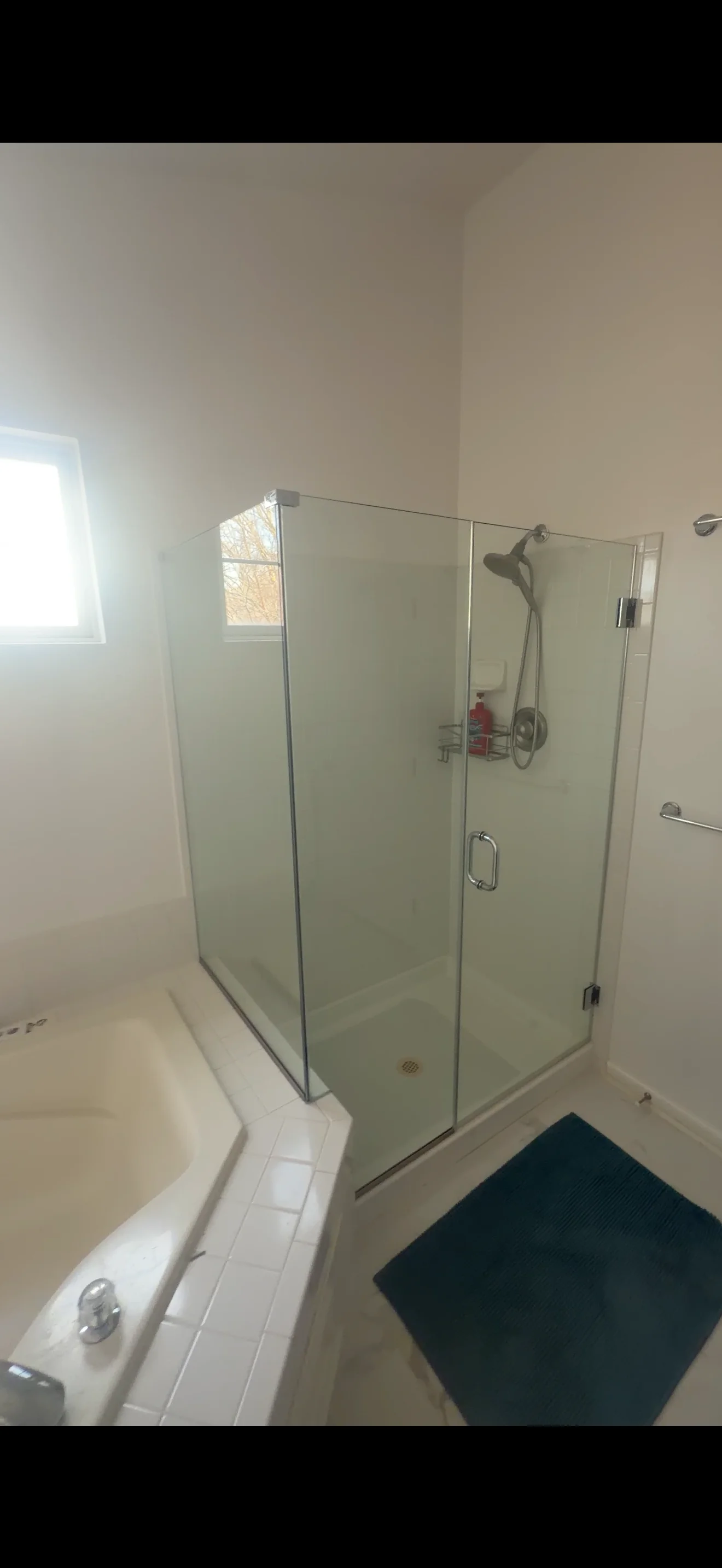 Frameless glass shower enclosure with chrome fixtures and hinged door in modern bathroom