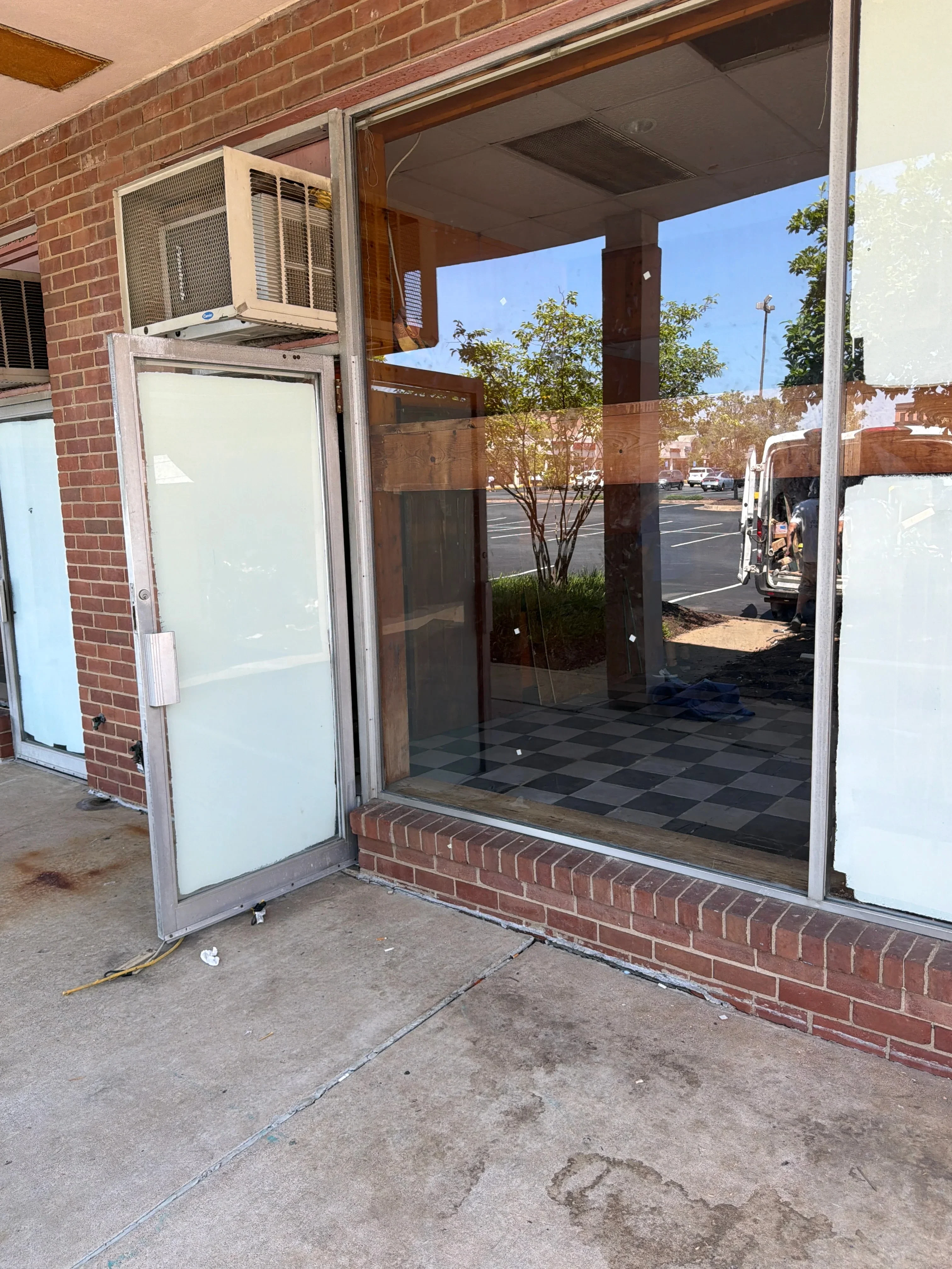 Commercial storefront with large frameless glass panels and glass entry door on brick building